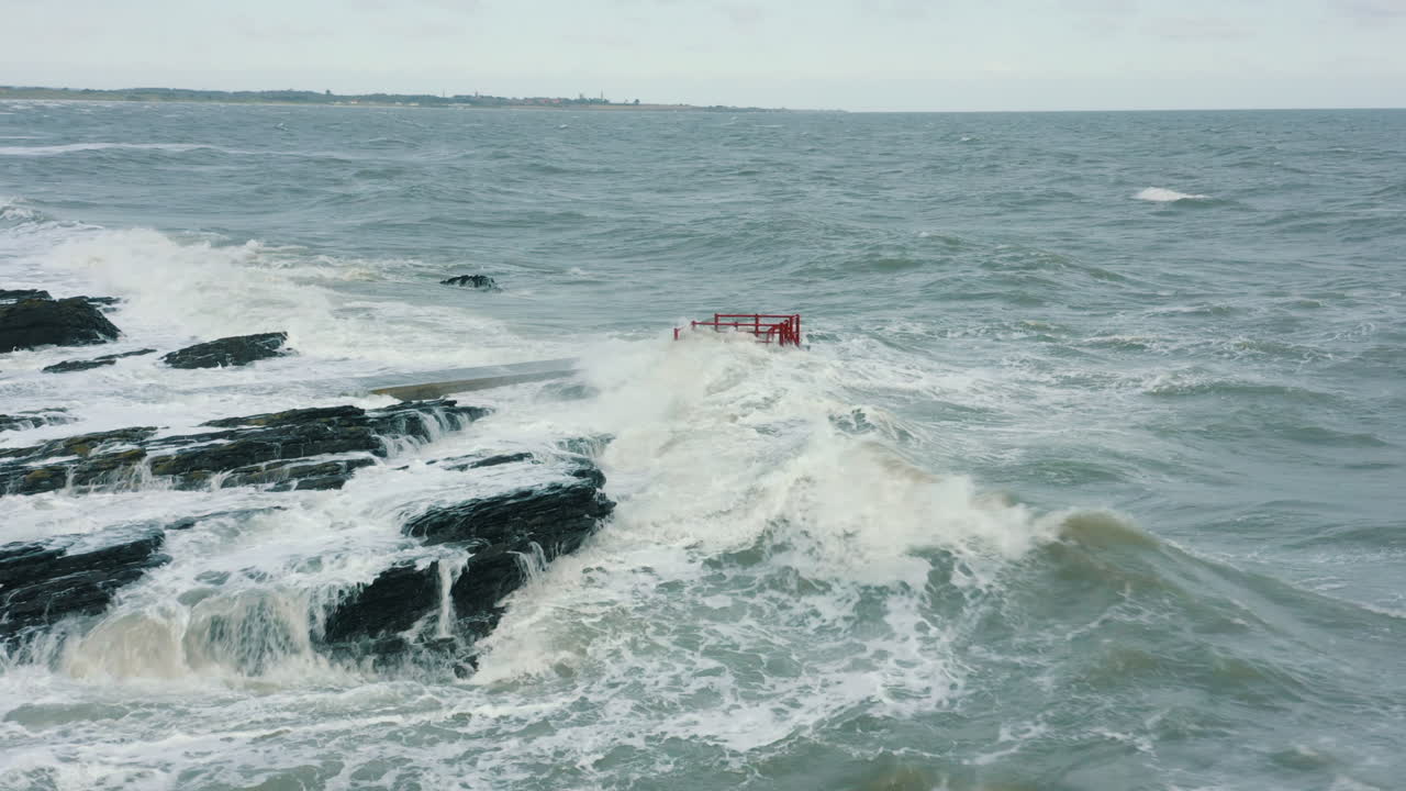폭풍우 동안 해안선을 따라 바위에 부서지는 파도의 공중 전망