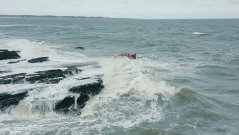 aerial view of waves crashing against rocks along the coastline during a storm
