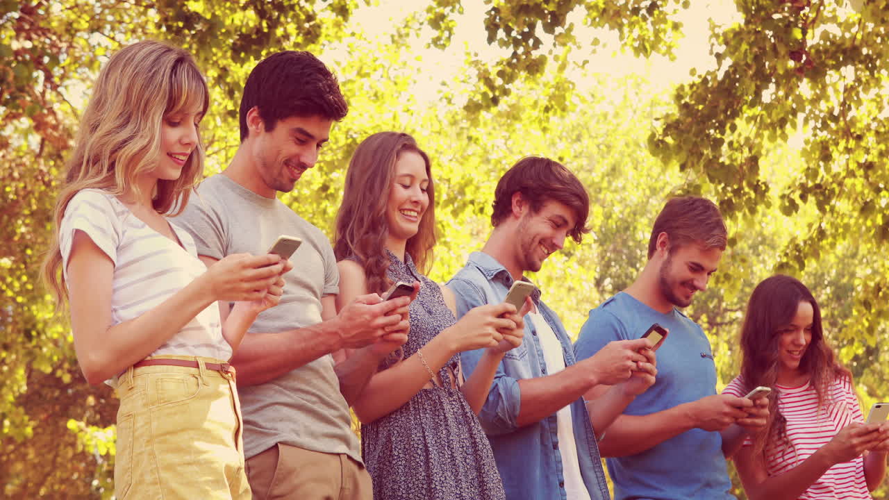 un joven guapo leyendo un libro apoyado en un árbol.
