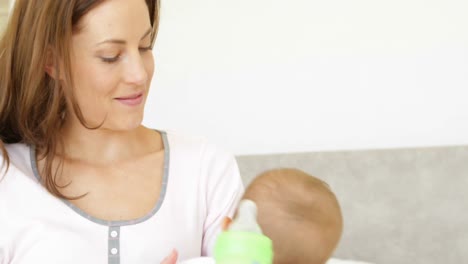 hermosa madre joven alimentando a su niña con su biberón