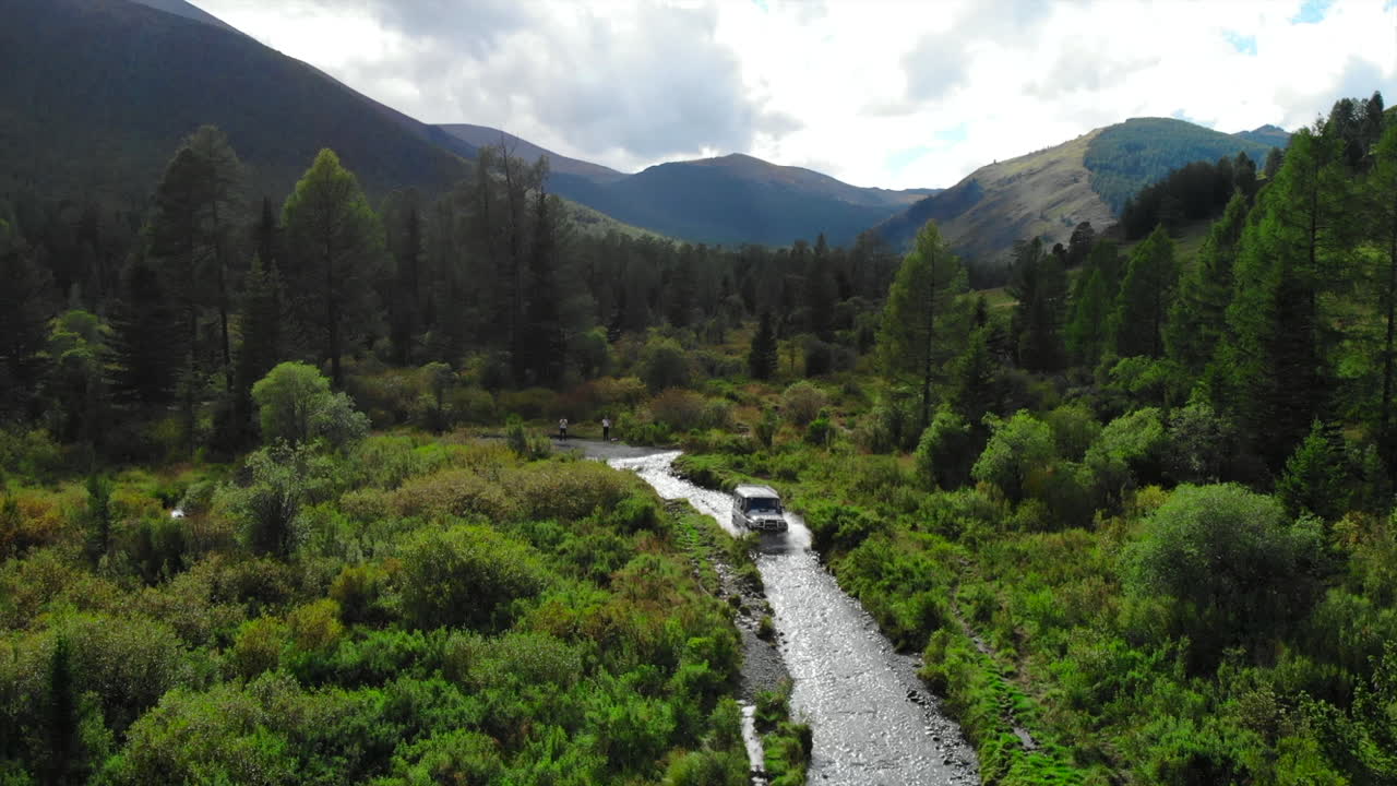 Off-road vehicle traversing a stream in a scenic mountain forest