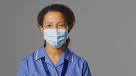 studio portrait of female nurse wearing uniform and face mask