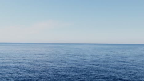 blue endless sea water with bright sky and horizon, aerial fly forward view