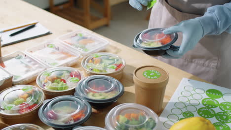Food-Delivery-Service-Worker-Putting-Stickers-on-Containers-with-Eco-Meals