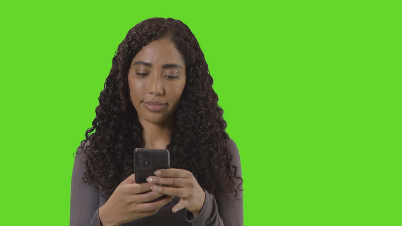 ritratto di donna che invia messaggi di testo sul cellulare contro lo schermo verde