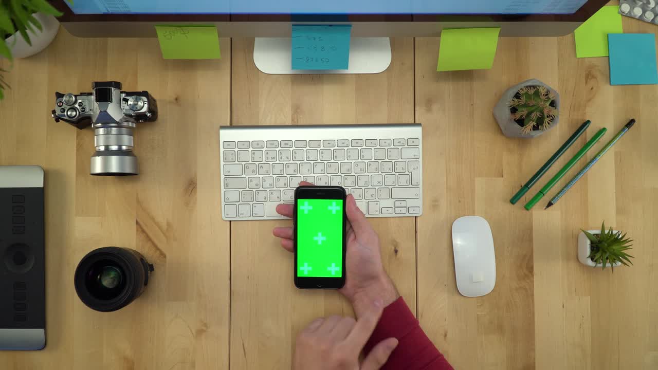 colocación plana de las manos del hombre usando el teléfono con pantalla verde en el lugar de trabajo