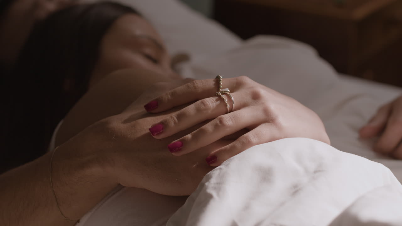pareja cogida de la mano en la cama