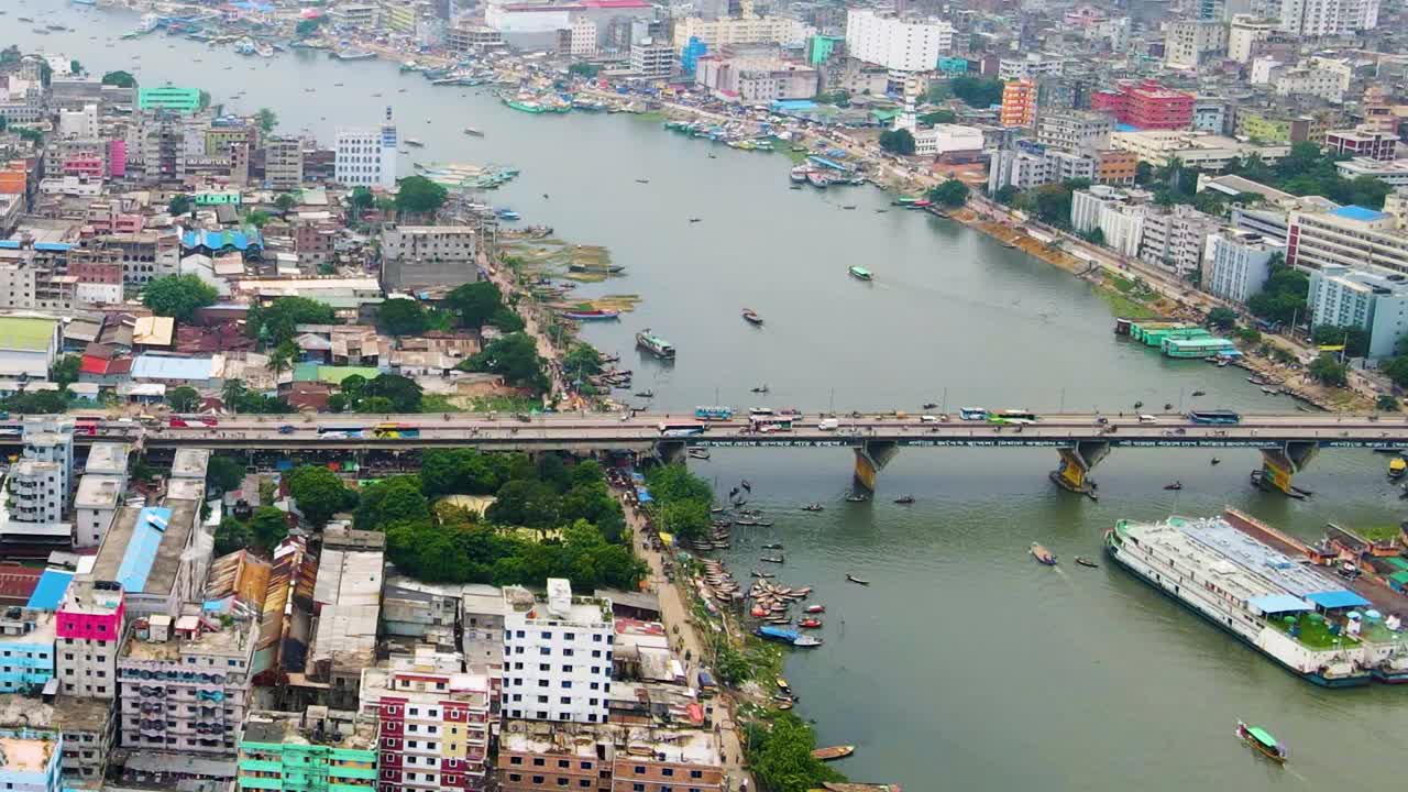 Un ponte trafficato sul fiume Buriganga a Dhaka, Bangladesh, con traghetti nell'acqua.