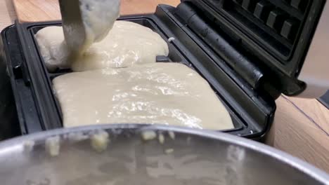 making waffles - pouring waffle batter into a waffle maker - close up, slow motion