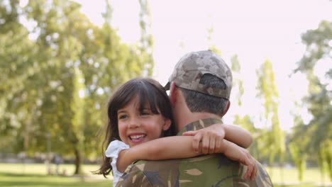 military dad carrying daughter in arms in the park