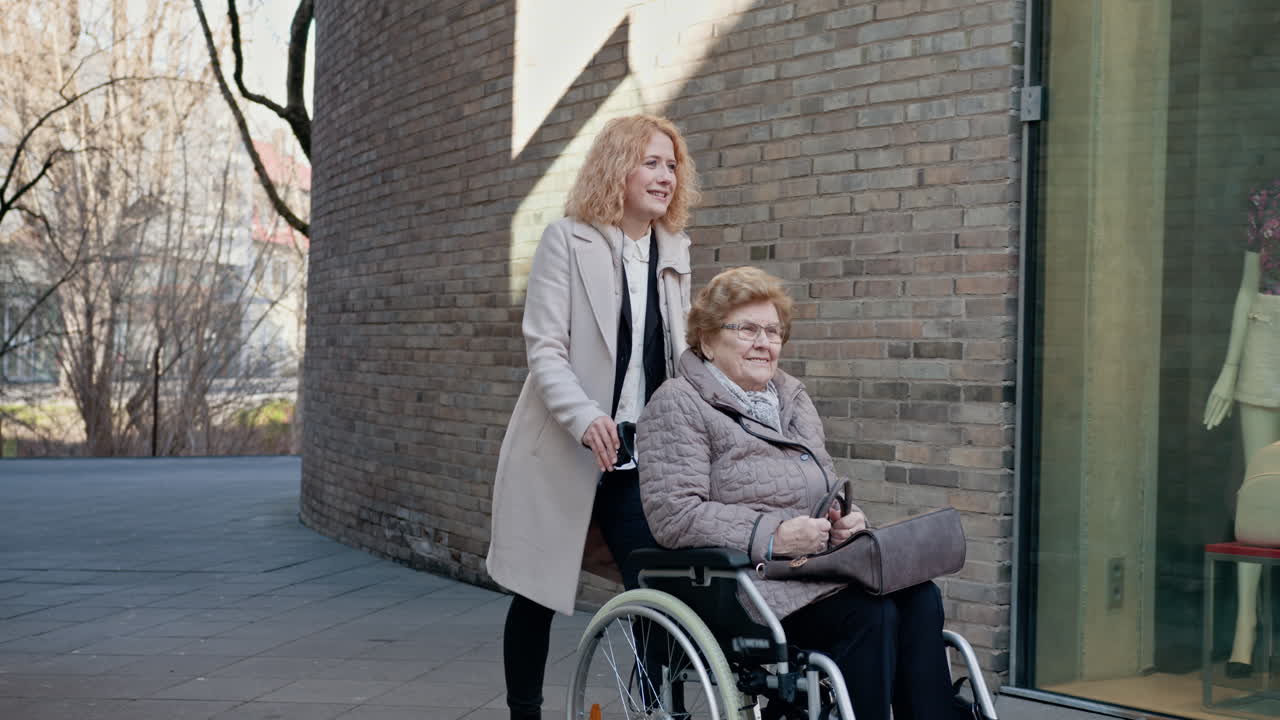 mujer joven ayudando a una mujer anciana en silla de ruedas