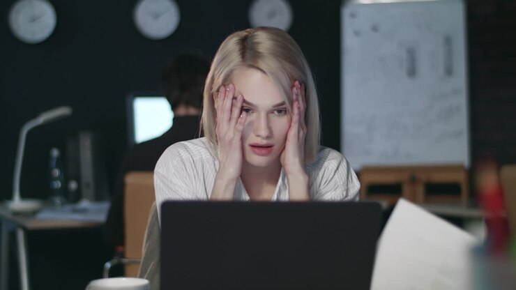Disappointed business woman throwing document front laptop in dark office