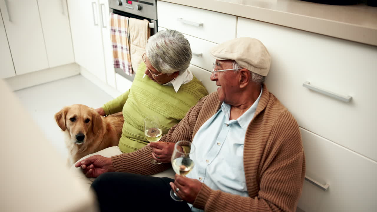 An elderly couple sitting on the kitchen floor with their dog
