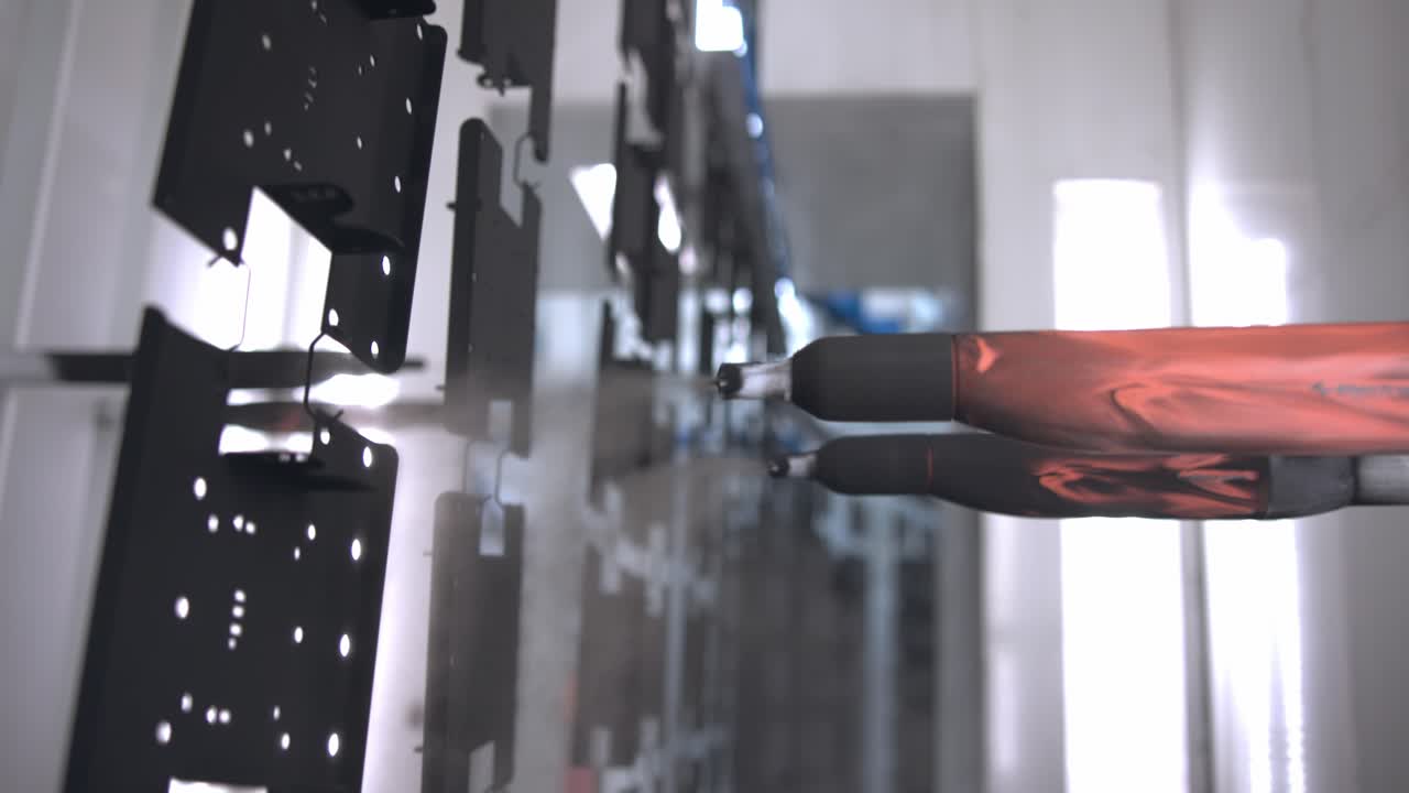 Slow motion close up tracking shot of an industrial painting robot, painting a metal sheet