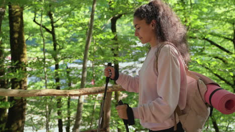 woman hiking in a forest with hiking sticks and backpack