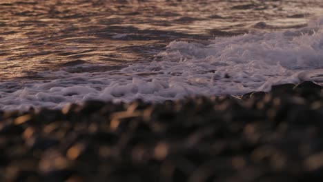 una ola chocando en la playa rocosa de funchal, en madeira, al atardecer