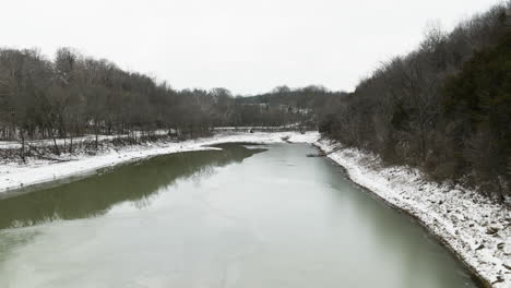 tranquil waters of river with trees on the snowy bank in winter in arkansas, usa