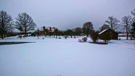 Zeitraffer-Eines-Zufrierenden-Sees-In-Einer-Verschneiten-Landschaft-Mit-Viel-Schnee-Und-Einigen-Häusern