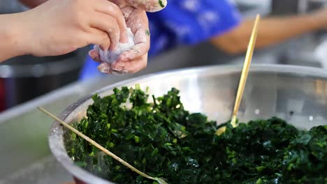 hands making stuffed vegetable rolls in a bowl