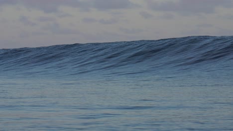 Towering-surfing-surf-monstrous-clean-barrel-waves-Teahupoo-Tahiti-French-Polynesia-crashing-huge-swell-on-shallow-coral-reef-South-Pacific-island-ocean-waterhousing-landscape-sunset-super-slow-motion