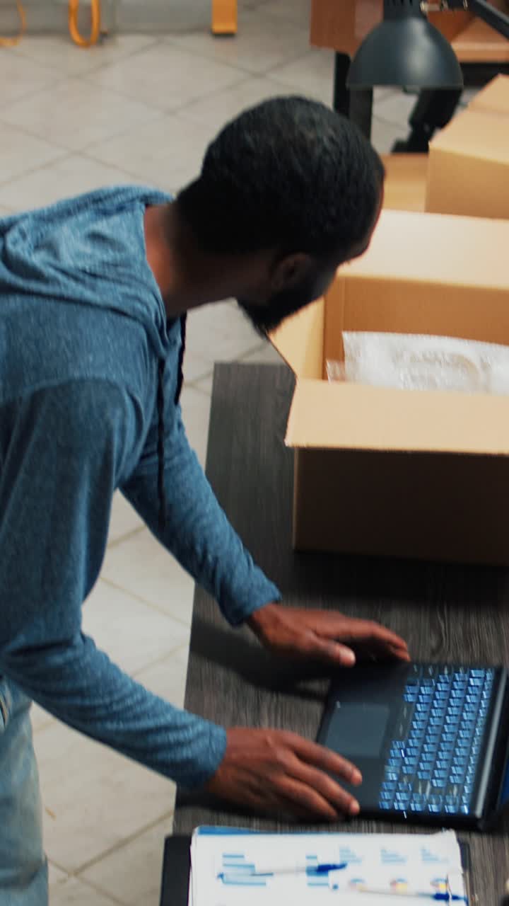 Vertical video: Young office employee arranging goods in packages