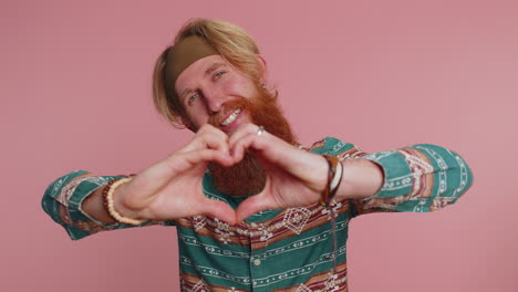 Smiling-redhead-man-makes-heart-gesture-demonstrates-love-sign-expresses-good-feelings-and-sympathy