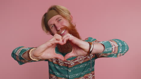 un hombre pelirrojo sonriente hace un gesto de corazón demuestra un signo de amor expresa buenos sentimientos y simpatía