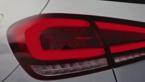 close up of shiny red tail light of car, light reflection on painted surface