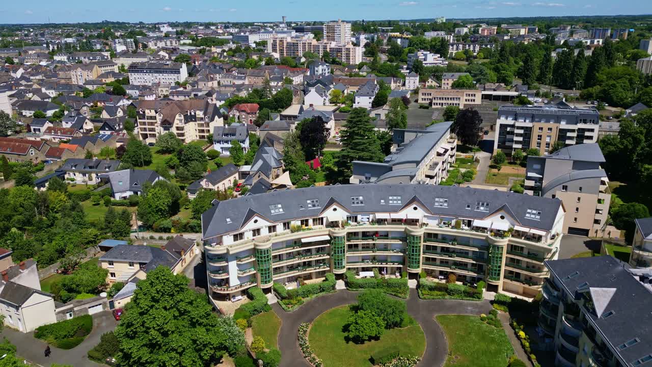 Drone flies over the Mayenne in Laval, showing residential park, buildings, trees, and full cityscape on a sunny day - France