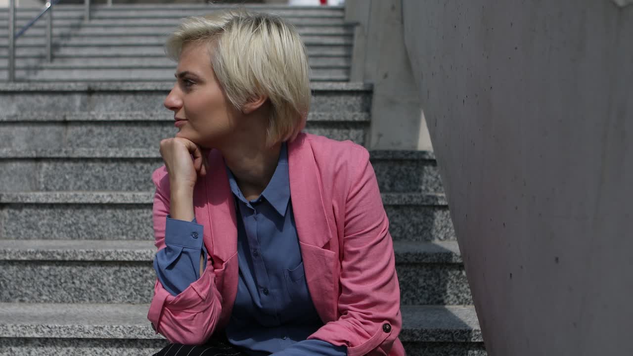 En underbar kvinna som sitter på trappan och funderar över livet medan hon ler - Närbild.