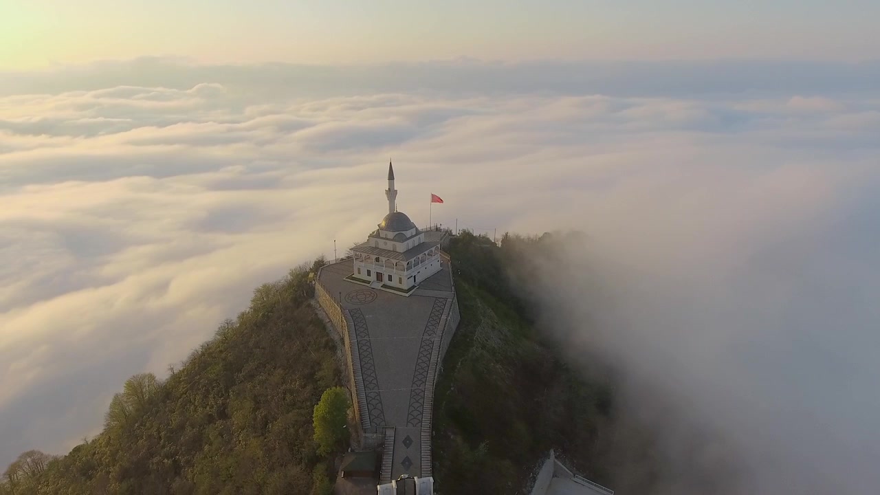 Luftaufnahme einer Moschee auf einem Berggipfel über den Wolken