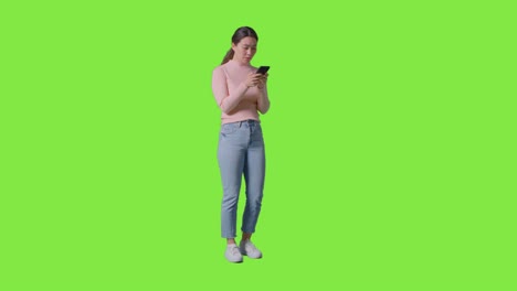 Studioaufnahme-In-Voller-Länge-Einer-Frau,-Die-Ihr-Mobiltelefon-überprüft-Und-Vor-Dem-Greenscreen-Eine-Enttäuschende-Nachricht-Erhält