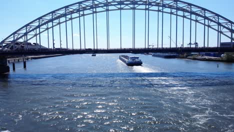 barge with backwash passing under arch bridge over noord river at hendrik-ido-ambacht, netherlands