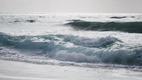 rhythmic waves gently crash onto the shore, creating a soothing symphony of sound. the foamy surf dances across the golden sand, inviting beachgoers to enjoy the calming beauty of the ocean.