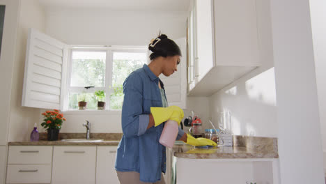 video of happy biracial woman cleaning kitchen