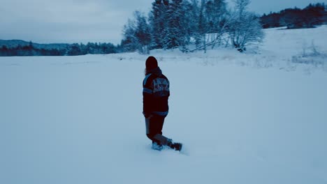 a man is strolling across a snow-covered farmland - tracking shot