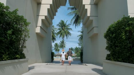 couple men and woman walking at an old gate during vacation at an luxury resort in thailand