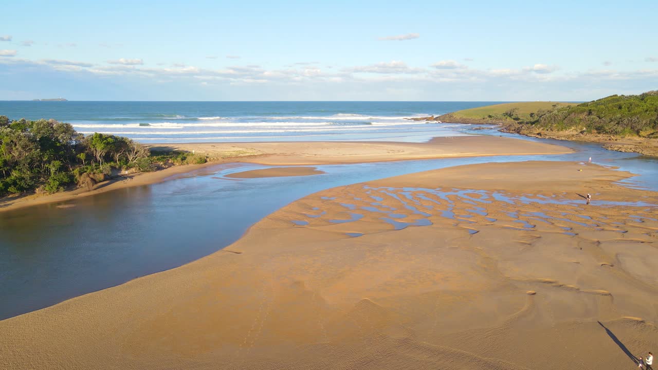 gente caminando en el arroyo de arena moonee durante la marea baja en un día soleado en verano - playa moonee en nsw, australia