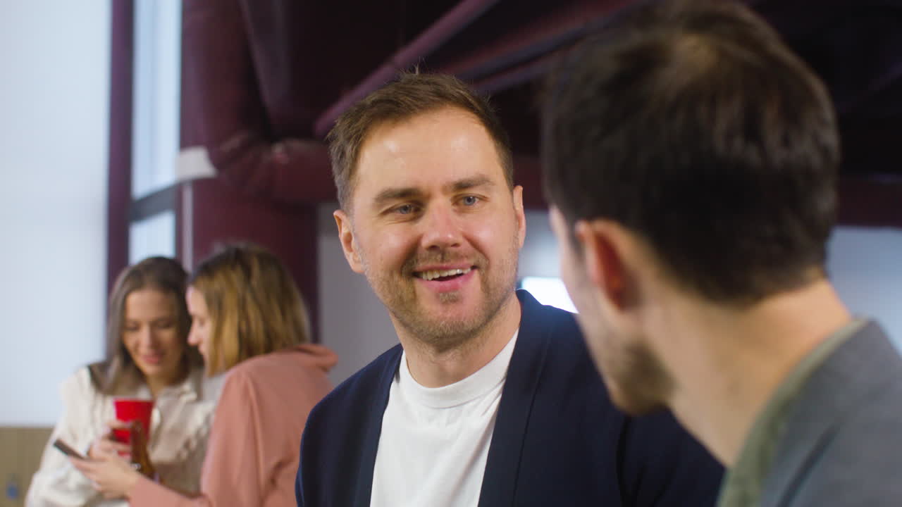 dos hombres hablando y riendo juntos en la fiesta de la oficina
