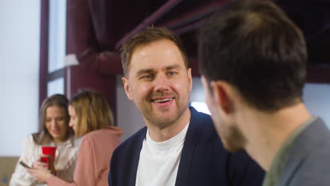 two men talking and laughing together at the office party