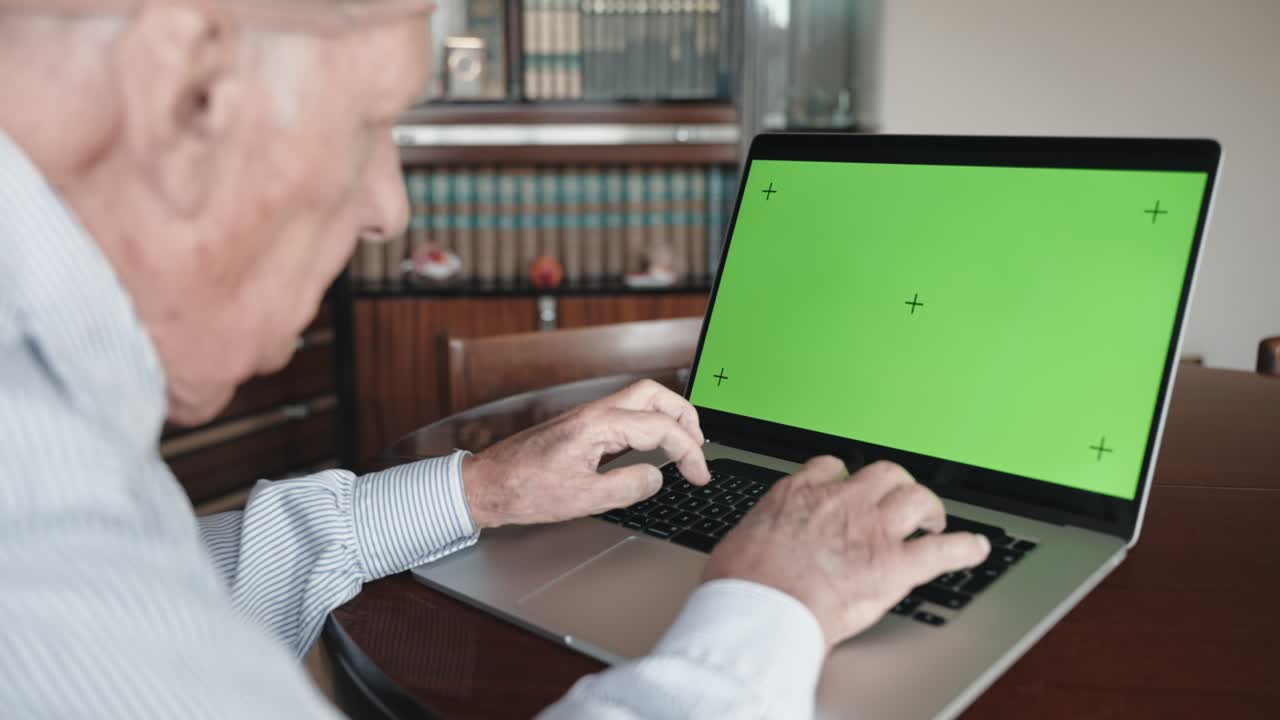 hombre mayor escribiendo lentamente en el teclado de la computadora con la tecla de croma de pantalla verde, pensionista navegando por internet a través de la portátil. hombre solitario buscando información en la computadora, manos de anciano escribiendo en