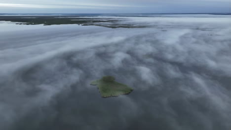 aerial view of misty wetlands with small green island