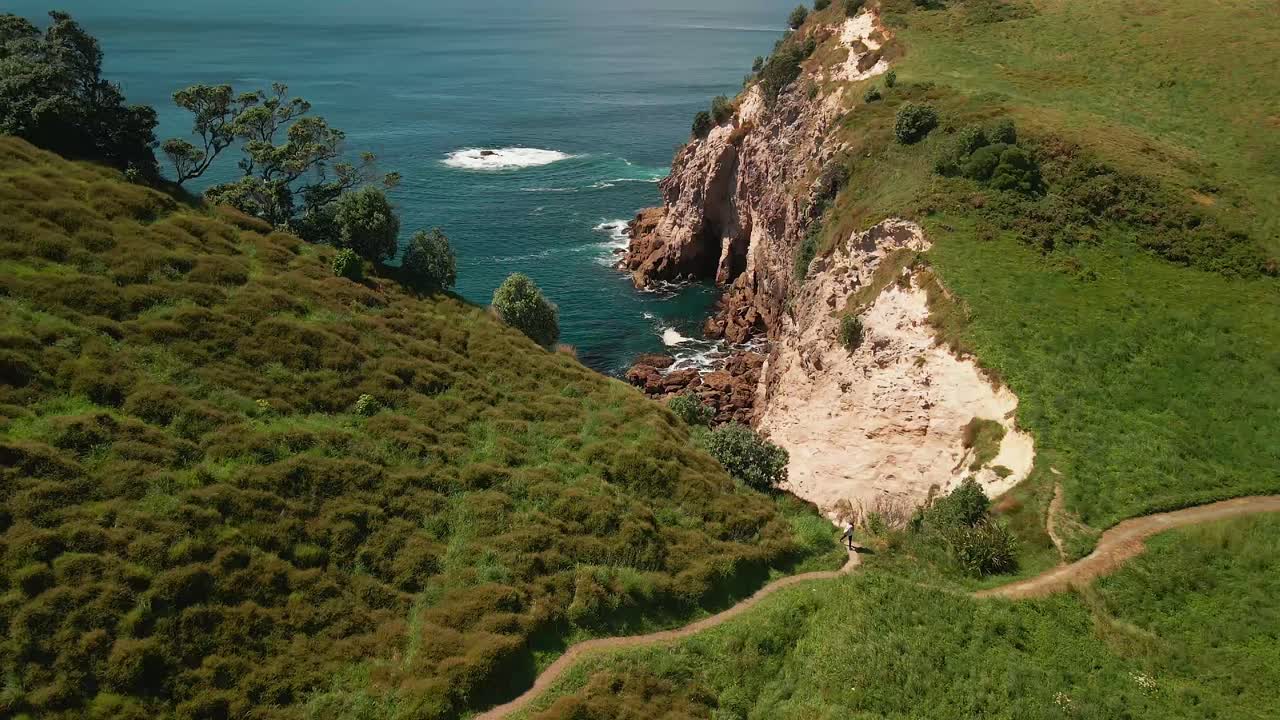 Ripresa aerea cinematografica di un escursionista che sale un sentiero lungo la cresta di una montagna a picco