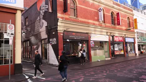 pedestrians walking past a building in melbourne