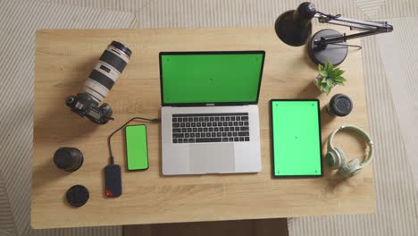 vista superior zoom out toma de pantalla verde portátil, teléfono inteligente y tableta están al lado de la cámara en una mesa en el espacio de trabajo en casa