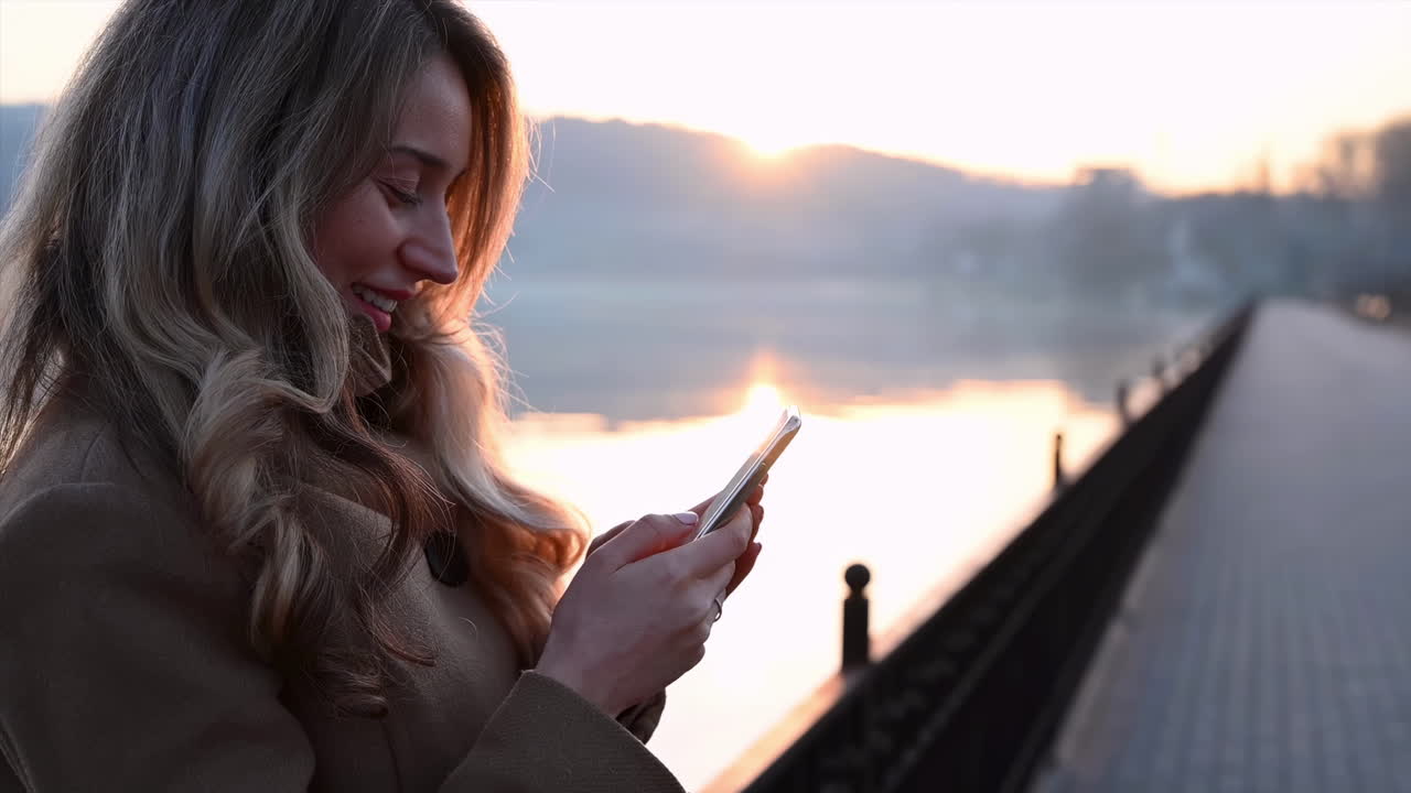 Smiling young woman reading something from her phone in park