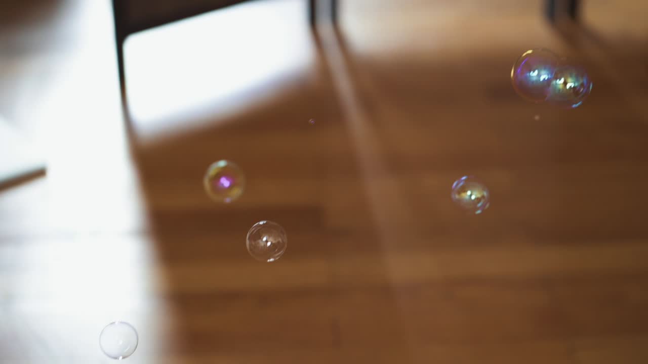 Big and small soap bubbles falling down ont the brown wooden parquet