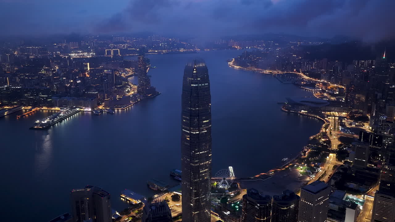 Stunning aerial night view of Hong Kong skyline with illuminated skyscrapers, Victoria Harbour, and shimmering city lights reflecting on the water, showcasing the vibrant urban cityscape
