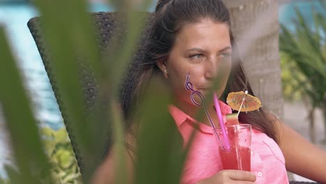 Grüner-Zweig-Schwingt-Im-Wind-Vor-Einer-Dame-Mit-Cocktail