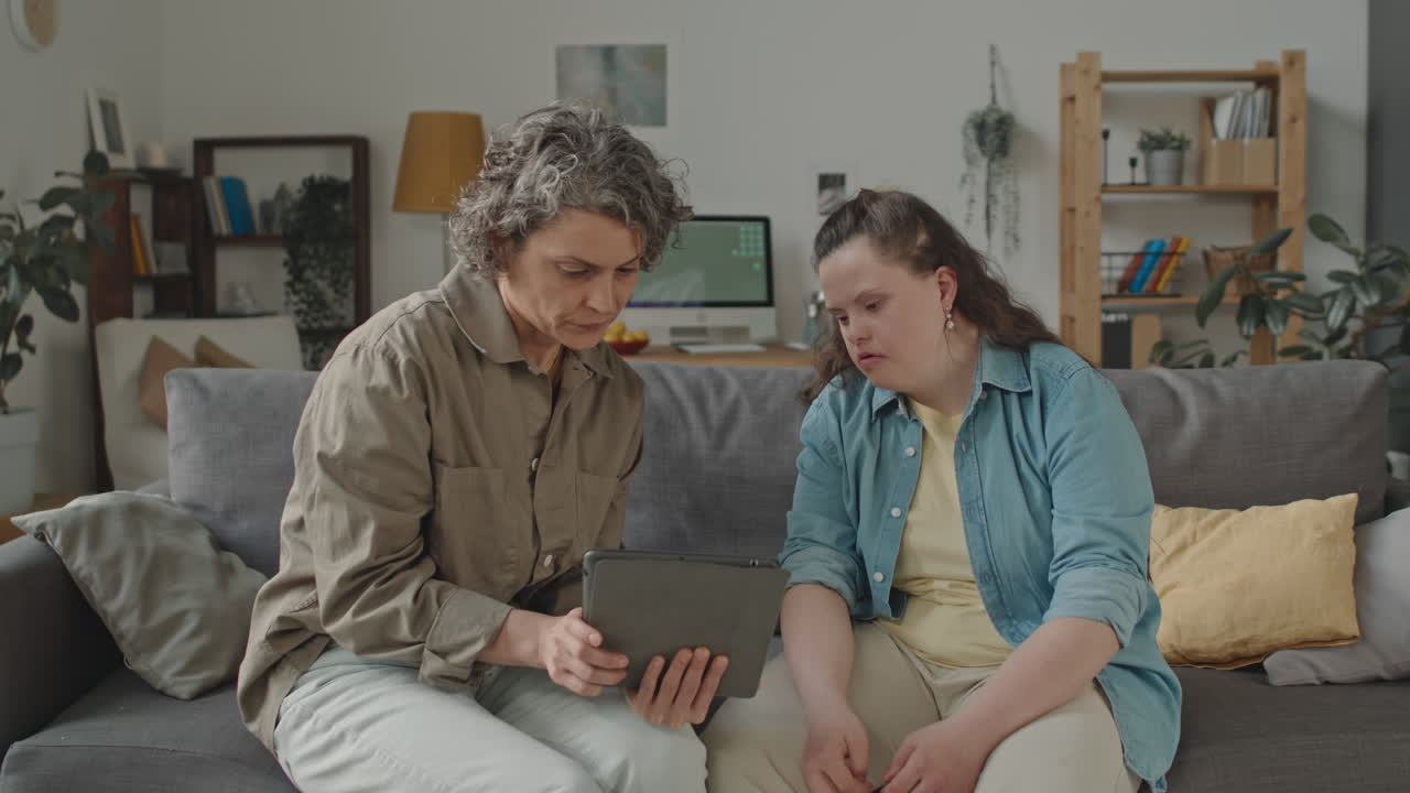 Woman with Down syndrome looking at a tablet with another woman